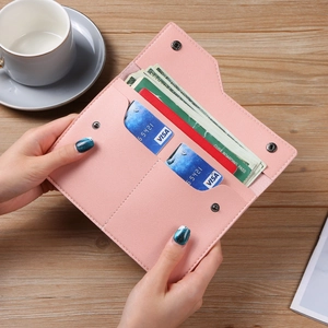Pink minimalist long wallet with multi-card slots and snap closure on wood surface