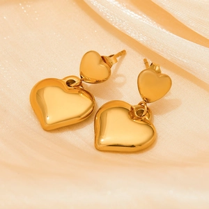Polished warm gold double heart earrings on silk fabric in a minimalist vintage style