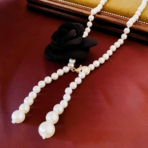 Détail d'un collier de perles élégant avec rose noire en tissu et glands asymétriques