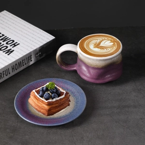 Detailed close-up of a rustic ceramic coffee cup with latte art and a blueberry dessert plate