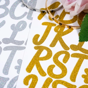 Macro shot of gold and silver glitter alphabet stickers showing sparkling texture for DIY crafts