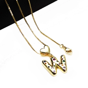 Detail of gold letter W pendant with colorful zircons and a small heart charm on box chain