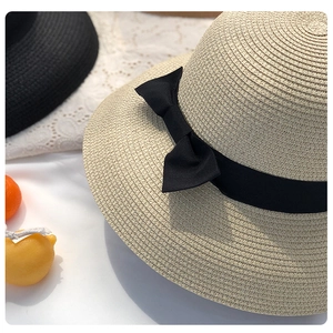 Elegant beige straw sun hat for women featuring a stylish black ribbon bow detail