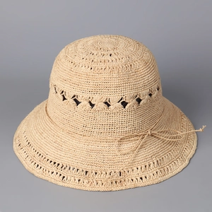 Détail du motif au crochet ajouré et du nœud délicat sur le chapeau de paille beige
