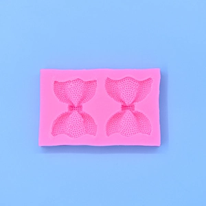 Detail shot of the flexible pink silicone mold featuring two bow tie shapes for baking