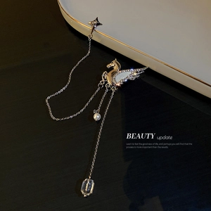 Silver Pegasus brooch with rhinestones, pearl tassels, and crystal on a ceramic plate
