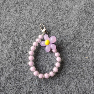 Close-up of purple beaded flower charm with yellow center and silver metal clasp