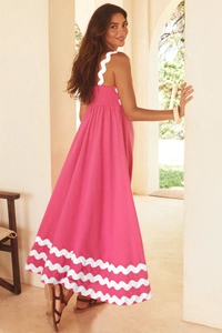 Detailed view of pink maxi dress featuring white wavy scallop trim and elastic pleated bodice