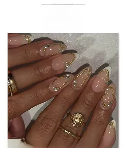 Detail of French press-on nails with gold relief lines, small rhinestones and nude pink base