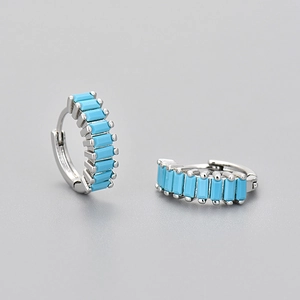 Macro detail of silver rectangle hoop earrings set with turquoise stones on gray background