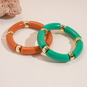 Dettaglio di bracciali in acrilico arancione e verde con distanziali dorati