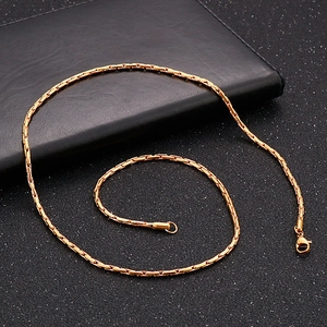 Détail macro d'un collier chaîne serpent en acier inoxydable doré sur fond noir chic