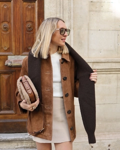 Photo en extérieur d'une veste en daim marron avec haut en maille blanc et écharpe