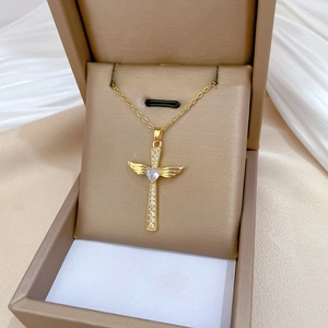 Golden wing cross necklace with heart crystal pendant presented in a luxury jewelry box