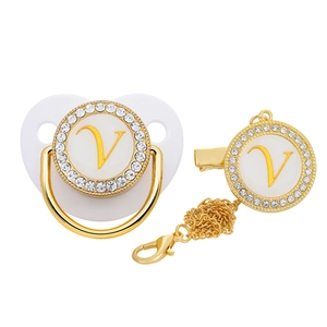 Detail of gold baby pacifier and clip set with white letter V and sparkling rhinestones