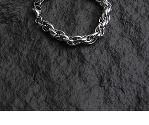 Detailed top view of silver hiphop twist chain bracelet on textured stone background