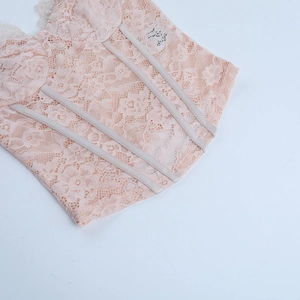 Vue détaillée de la dentelle florale rose pêche et de la structure baleinée du corsage