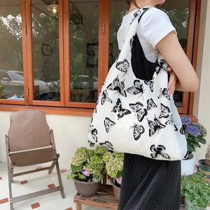 Minimalist canvas tote bag with black and white butterfly print for women shown on shoulder