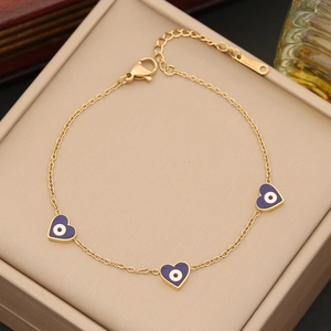Golden chain bracelet with purple heart charms and evil eye details in a jewelry box