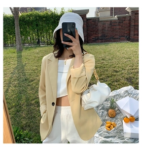 Outdoor summer lifestyle view of a chic white pleated cloud bag with chunky gold chain