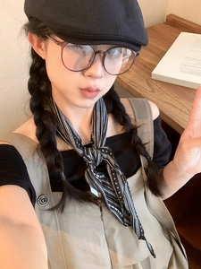 Close-up of a vintage striped fabric neckerchief styled with a black newsboy cap and glasses