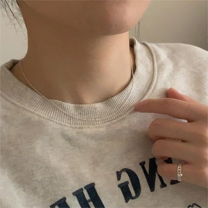 Close-up of minimalist 925 sterling silver water wave chain necklace and slim ring worn