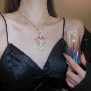 Macro detail of luxury fan-shaped gold necklace set with red and clear rhinestones