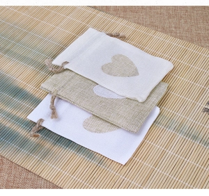 Close-up of linen drawstring jewelry pouches with heart pattern on a bamboo mat