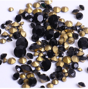 Detailed view of multi-faceted black and gold pointed-bottom nail art rhinestones