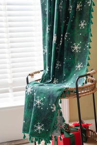 Detailed view of green Christmas curtain fabric with snowflake patterns and green tassels