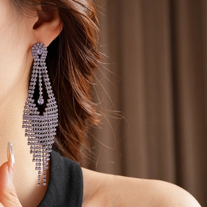 Gros plan de boucles d'oreilles à pompons en strass violets portées par un mannequin
