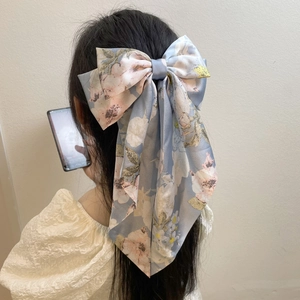 Detailed back view of a large blue floral fabric bow hair clip on a model