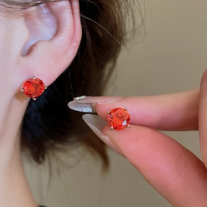 Detailed macro view of sparkling orange zircon stud earrings with silver four-claw setting