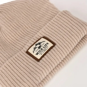 Close-up of oatmeal ribbed knit beanie featuring a retro Wild Life mountain patch