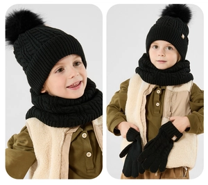 Detailed view of kids black knit hat with pom-pom, scarf, and gloves set for winter