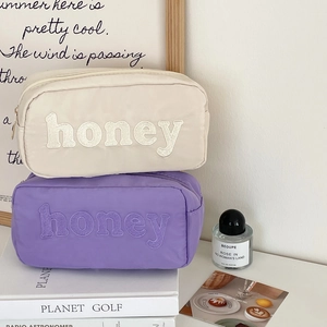 Detail of nylon cosmetic bags with honey embroidery and durable metal zipper closure