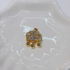 Detailed view of a gold lock pendant with clear gemstones on a white ceramic tray