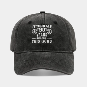 Detail of embroidered 90th birthday slogan on washed dark grey cotton baseball cap