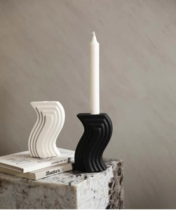 Close-up of modern S-shaped ceramic candle holder with elegant wavy texture in black and white