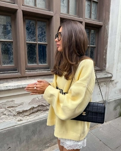 Detail of loose fit pale yellow knit sweater with embroidered text and lace skirt detail