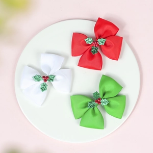 Detail of three Christmas ribbon bows with holly leaf accents in red, white and green
