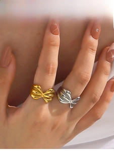 Detail of 18K gold and silver bow rings with textured wings on a hand