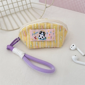 Close-up of a cute knitted cream headphone case with pink dog patch and purple strap
