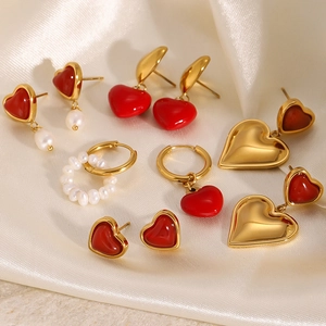 Golden heart earrings and pearl studs set on elegant silk fabric background