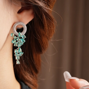 Orecchini geometrici color argento con nappe a goccia sfaccettate verde chiaro su modella
