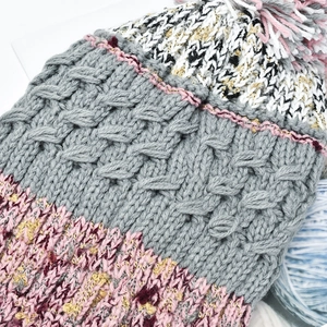 Chunky knit beanie with colorful pom-poms and a classic cable pattern in pink and grey
