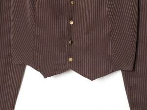 Dettaglio della camicia corta a righe marroni con bottoni dorati e orlo a punta