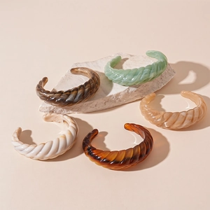 Ribbed geometric acrylic cuff bracelets in multiple colors on a stone slab display