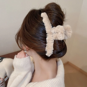 Detail of warm beige plush hair claw clip used on a hair bun for winter styling
