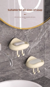 Detail of cream-colored wall-mounted soap dish with drainage and bottom dual hooks